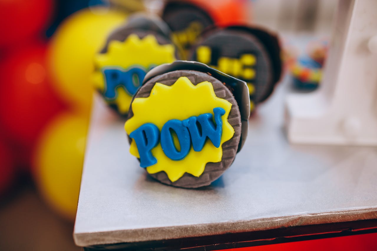 Vibrant cupcakes with comic-style decor featuring 'POW' lettering. Perfect for themed parties.